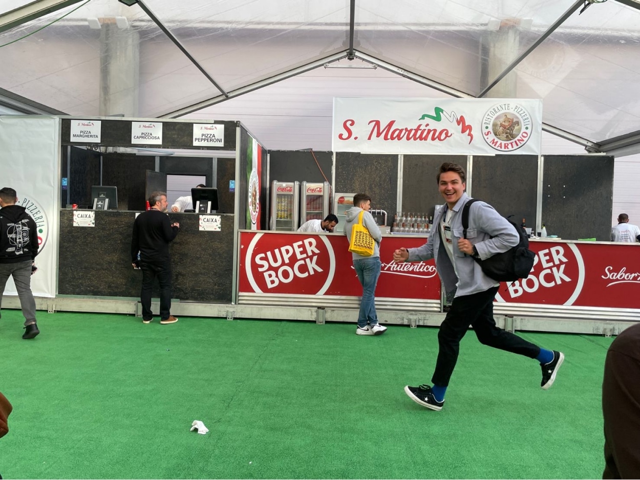 Niki with a backpack running through a conference hall with some food vendors in the background.